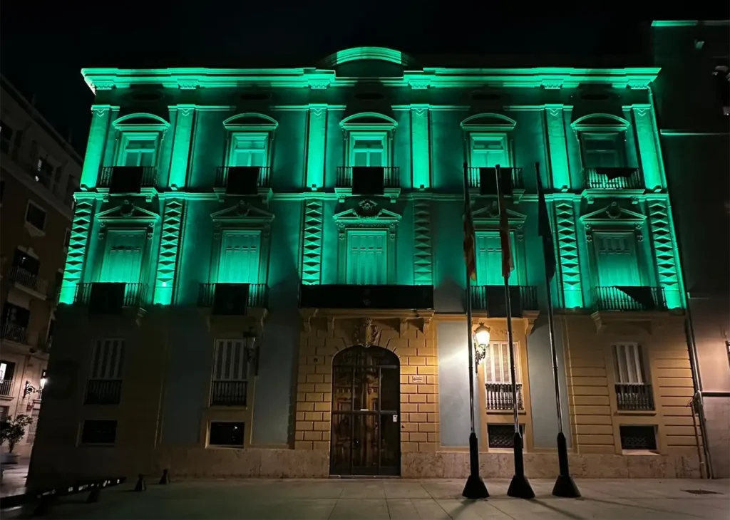 Fachada del Palacio de Congresos de Valencia iluminada de verde durante el Día Mundial de la Meningitis 2025, en apoyo a las personas afectadas y sus familias.